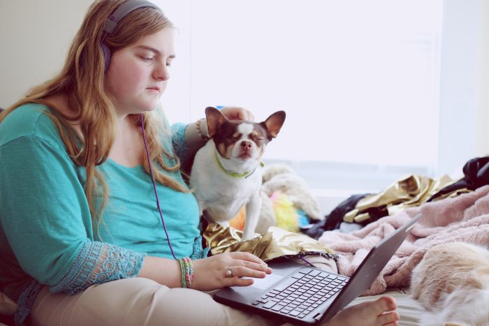 An obese woman with her pet dog while using a laptop